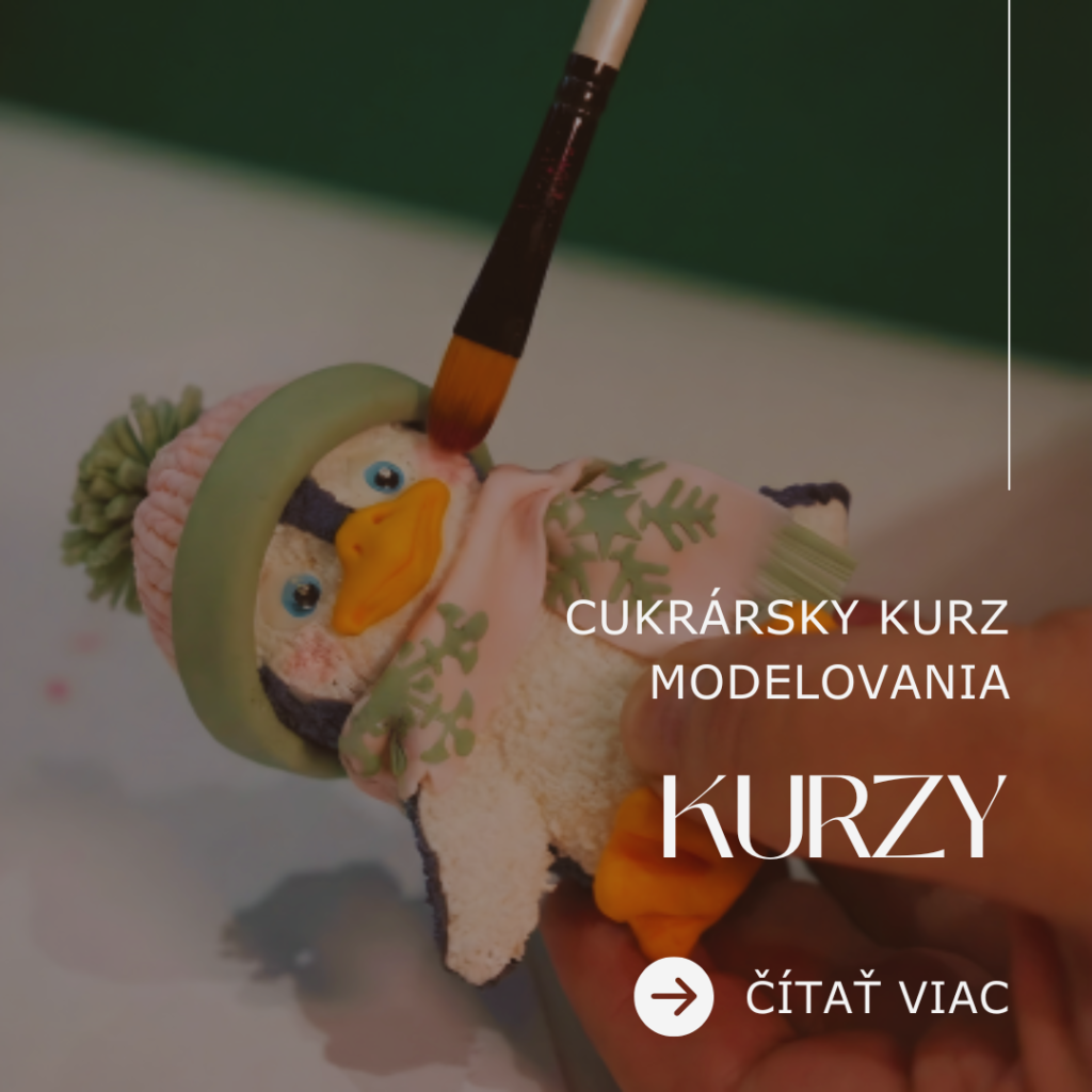 Detailný pohľad na ruku držiacu precízne vymodelovanú cukrovú postavičku tučniaka. Tučniak má realistickú štruktúru povrchu, má oblečenú ružovo-zelenú zimnú čiapku s brmbolcom a ružový šál so zelenými snehovými vločkami. Zhora je priložený kozmetický štetec, ktorým sa práve nanáša ružová púdrová farba na líčko postavičky. Ukážka techník modelovania, textúrovania a tieňovania jedlými farbami z cukrárskych kurzov Artmeli.